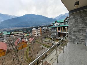 een balkon met uitzicht op de stad en de bergen bij Aleo Villa in Manāli
