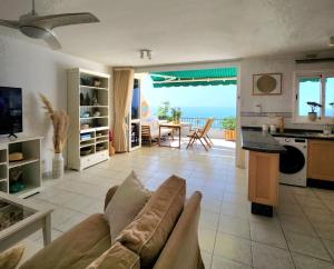 a living room with a couch and a kitchen with the ocean at Ocean Wave in Acantilado de los Gigantes