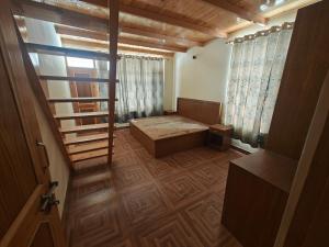 een kleine kamer met een houten vloer en een trap bij Aleo Villa in Manāli