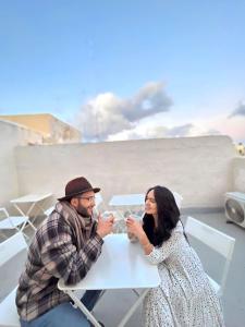 Ein Mann und eine Frau sitzen am Tisch und trinken Kaffee. in der Unterkunft San Francisco Studios Valletta in Floriana