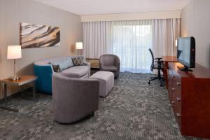 a hotel room with a bed and a desk and a television at Courtyard Charlotte Gastonia in Gastonia