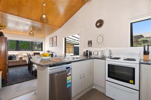 a kitchen with white appliances and a living room at Sunnyside Spa Retreat - Mangawhai Holiday Home in Mangawhai