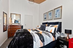 a bedroom with a bed and a dresser at Sunnyside Spa Retreat - Mangawhai Holiday Home in Mangawhai