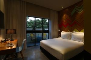 a hotel room with a bed and a desk and a window at Cucu Hotel in Tel Aviv