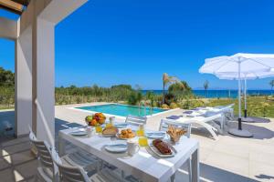 a white table with food on it next to a swimming pool at Villa Panaxia Votsalo in Theologos