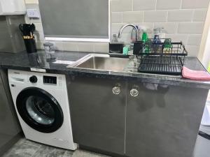 a kitchen counter with a sink and a washing machine at Beautiful 2-Bed House in London in London
