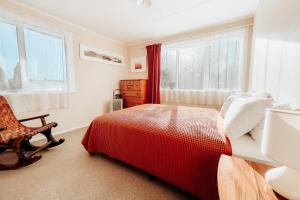 a bedroom with a bed and a chair and windows at Alpine House Tongariro - Turangi Holiday Home in Turangi