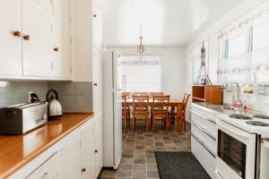 eine Küche mit weißen Schränken und ein Esszimmer in der Unterkunft Alpine House Tongariro - Turangi Holiday Home in Turangi