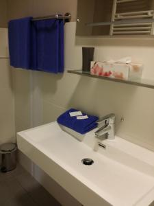 uma casa de banho com um lavatório branco e toalhas azuis em HD City Apartments em Heidelberg