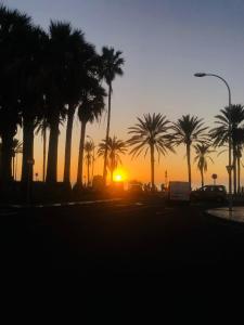 a sunset with palm trees and a truck at Furgoneta camperizada in Playa de las Americas