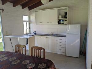 una cucina con armadietti bianchi e frigorifero bianco di Portal Del Campo a Piriápolis