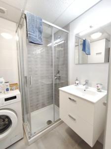uma casa de banho com um chuveiro, um lavatório e uma máquina de lavar roupa em Castel Harbour Tenerife em Los Cristianos