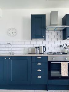 una cucina con armadi blu e un orologio sul muro di Apartment 4 St Georges a Cheltenham