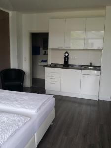 a bedroom with a bed and a kitchen with white cabinets at HD City Apartments in Heidelberg