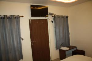 ein Schlafzimmer mit einem Fernseher an der Wand und einer Tür in der Unterkunft Raghunath Palace Home Stay in Varanasi