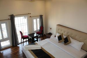 ein Schlafzimmer mit einem großen Bett und zwei roten Stühlen in der Unterkunft Raghunath Palace Home Stay in Varanasi