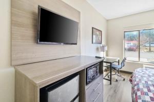 a room with a tv and a bed and a desk at Red Roof Inn & Suites Fayetteville-Fort Bragg in Fayetteville