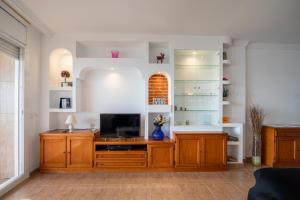 a living room with a tv on a wooden cabinet at 3 bedrooms appartement at Calafell 5 m away from the beach with sea view terrace and wifi in Calafell