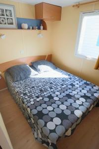a bedroom with a bed with a black and white comforter at Mobilhome LesPins YourHostHelper in Hyères
