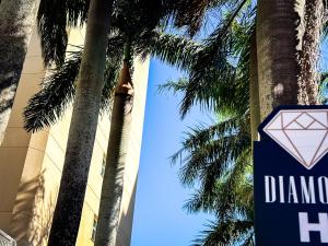 a sign for a diamond hotel next to a palm tree at Hotel Cianorte Diamond in Cianorte