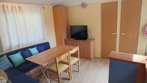 a living room with a table and a blue couch at Mobilhome LesPins YourHostHelper in Hyères