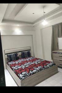 a bedroom with a bed with a red and black blanket at porto sokhna Pyramids Apartment Familis in Ain Sokhna