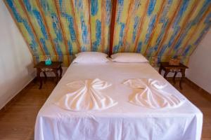 een bed met witte lakens en 2 kussens erop bij Vila Feliz - Chalés completos - ideal para famílias in Serra de São Bento