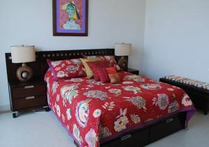 een slaapkamer met een bed met een rood dekbed bij Casa Wixson At Mayan Lakes 3-304 in Playa Encanto