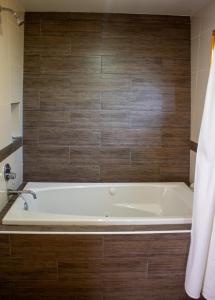 y baño con bañera y pared de madera. en San José del Pacífico Familiar Camino al Cielo en El Pacífico