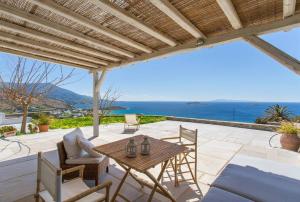 a patio with a table and chairs and the ocean at Island Villa Kon in Gavrio +3 photos