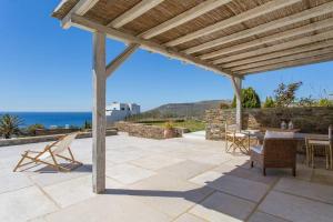 a patio with a table and chairs under a wooden pergola at Island Villa Kon in Gavrio