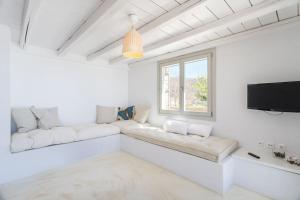 a white living room with white furniture and a flat screen tv at Island Villa Kon in Gavrio