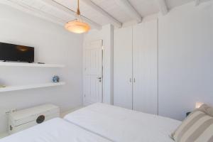 a white bedroom with a bed and a tv at Island Villa Kon in Gavrio