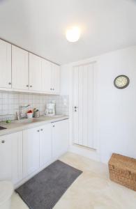 a white kitchen with white cabinets and a black rug at Island Villa Kon in Gavrio