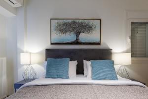 1 dormitorio con 1 cama con 2 lámparas y 1 árbol en Faliro lux apartment by the sea vipgreece en Atenas