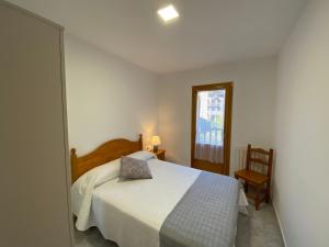 1 dormitorio con 1 cama blanca y 1 silla en BUENAVISTA2 en Biescas