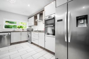 una cocina con electrodomésticos de acero inoxidable y armarios blancos en Luxury 3 Bed House - Parking - Garden - Pool Table -782S, en Birmingham
