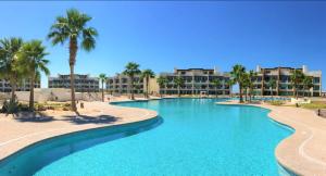 een zwembad met palmbomen en gebouwen bij Casa Wixson At Mayan Lakes 3-304 in Playa Encanto