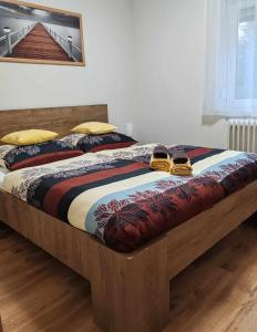 Una cama con marco de madera y zapatos. en Csillag Vendégház Kiskunmajsa en Kiskunmajsa