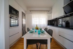 cocina blanca con mesa blanca y sillas en Faliro lux apartment by the sea vipgreece, en Atenas