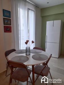 a dining room table with chairs and a white refrigerator at Dimora in Chalkida