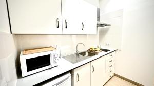 a white kitchen with a sink and a microwave at Suit Dreams Vilaflor By Deihu Experiences in Vilaflor