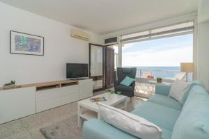 un soggiorno con un divano blu e una televisione di Mar Blava a Cala Ratjada