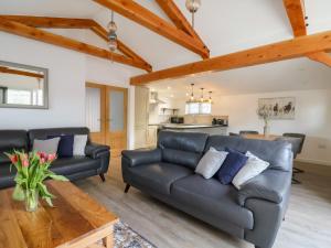 a living room with a leather couch and a table at The Stables Merrydown in Axminster