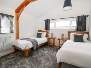 a room with two beds and a table and two windows at The Stables Merrydown in Axminster