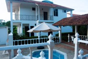 une maison blanche avec un parasol à côté d'une piscine dans l'établissement Casa Campestre para la Familia, à Nilo