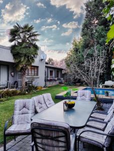a patio with a table and chairs in a yard at Leana Hub Guest House in Potchefstroom