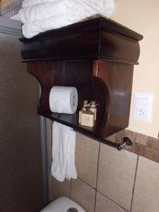a bathroom with a toilet and towels on a shelf at Crysol Center Hotel in Chimaltenango