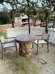 una mesa y dos sillas sentadas junto a un árbol en Villa con piscina privada Costa brava, en Maçanet de la Selva