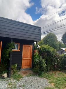 a small black house with a wooden door at cabaña el remo in Cunco